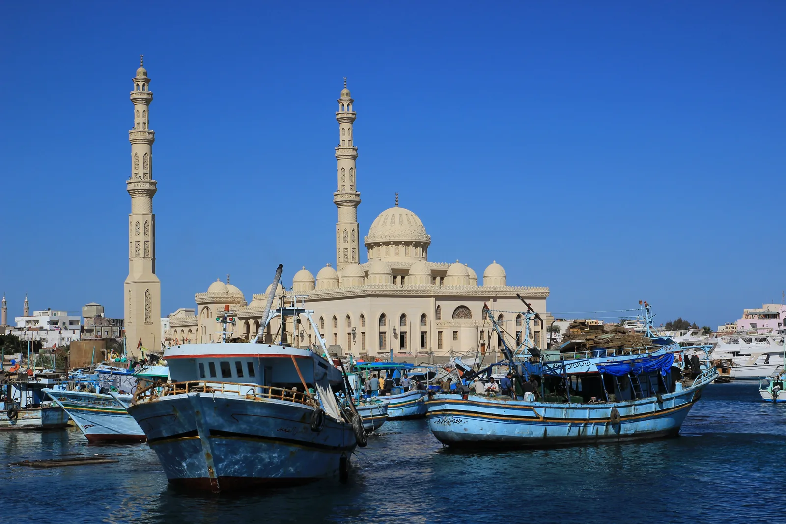 Hurghada harbour with fishing boats and the El Mina Mosque under a clear blue sky